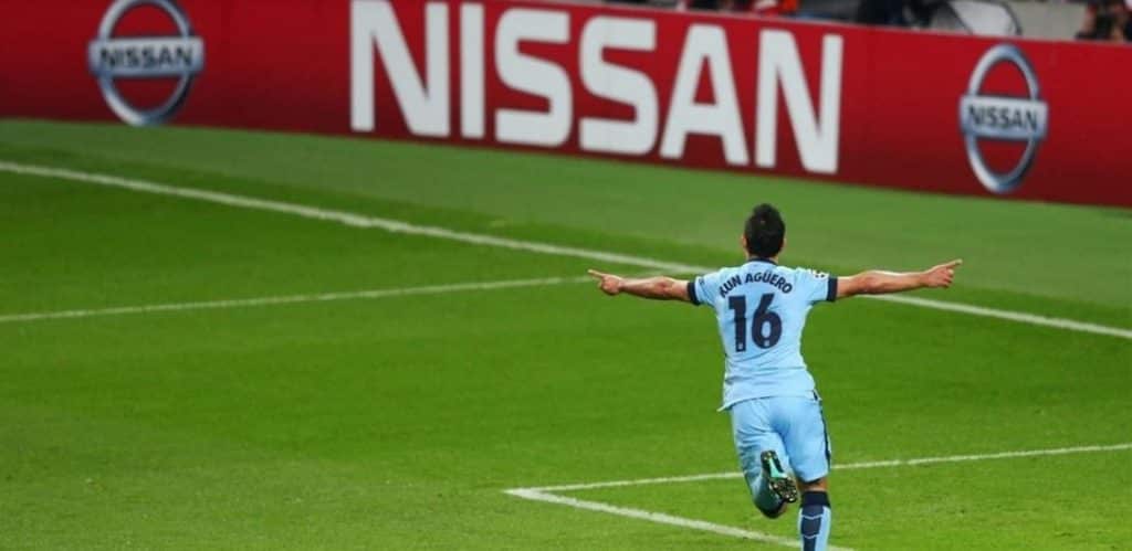 Agüero running towards supporters with a Nissan led in background.